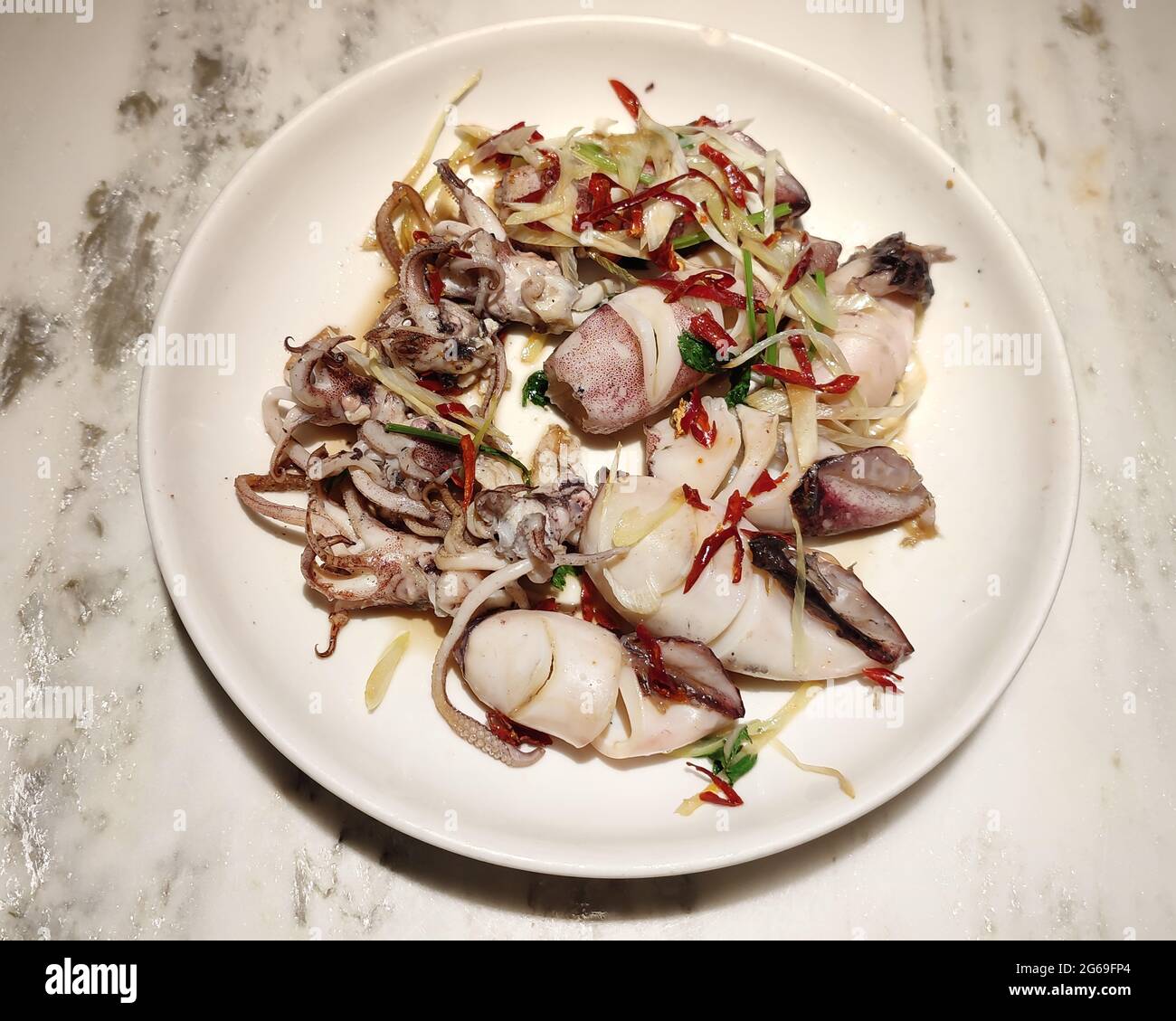 calamares recién estofados con pimienta roja en el plato blanco listo para comer Foto de stock