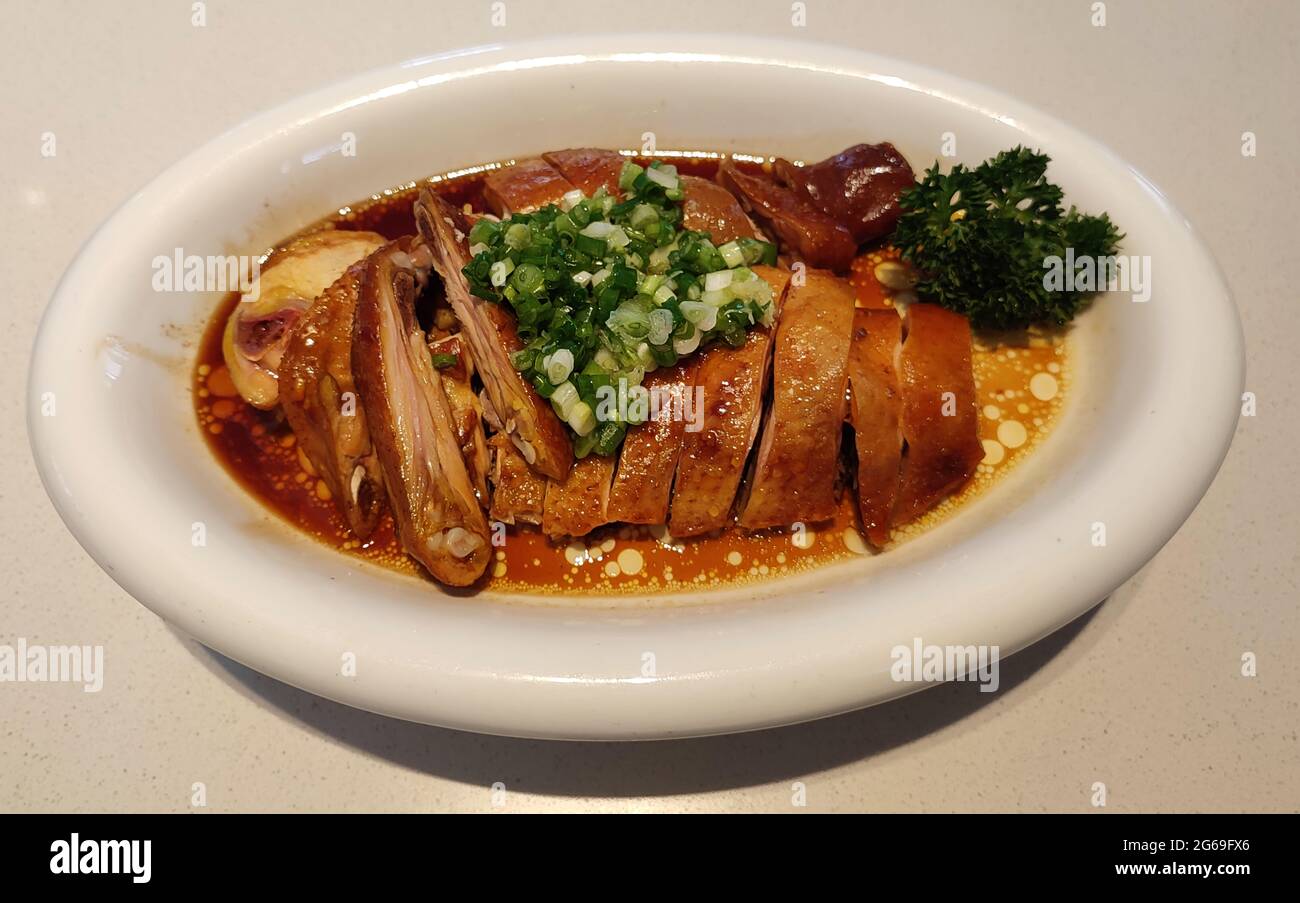 Pollo con salsa de soja fresca con cebolleta verde en el plato blanco Foto de stock