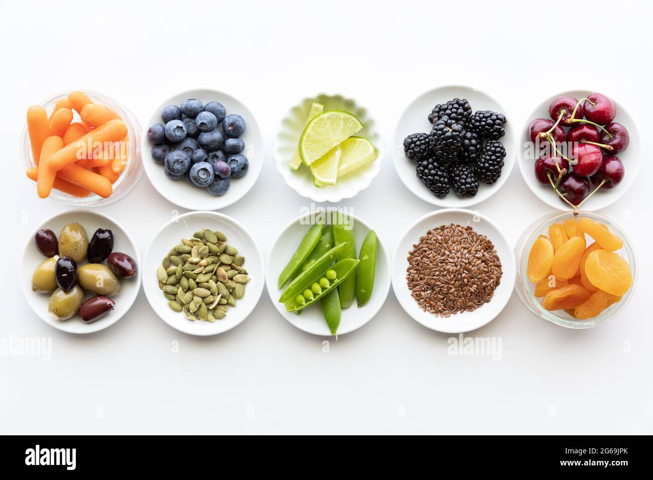 Hileras de ingredientes crudos y saludables en platos pequeños. Foto de stock