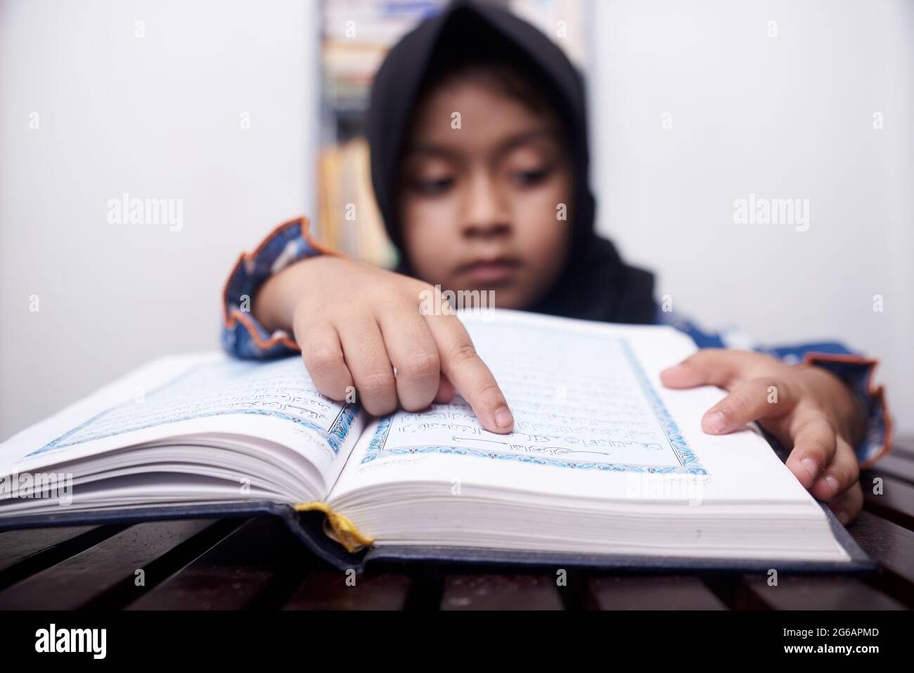 La niña musulmana en el hijab lee Quran Foto de stock