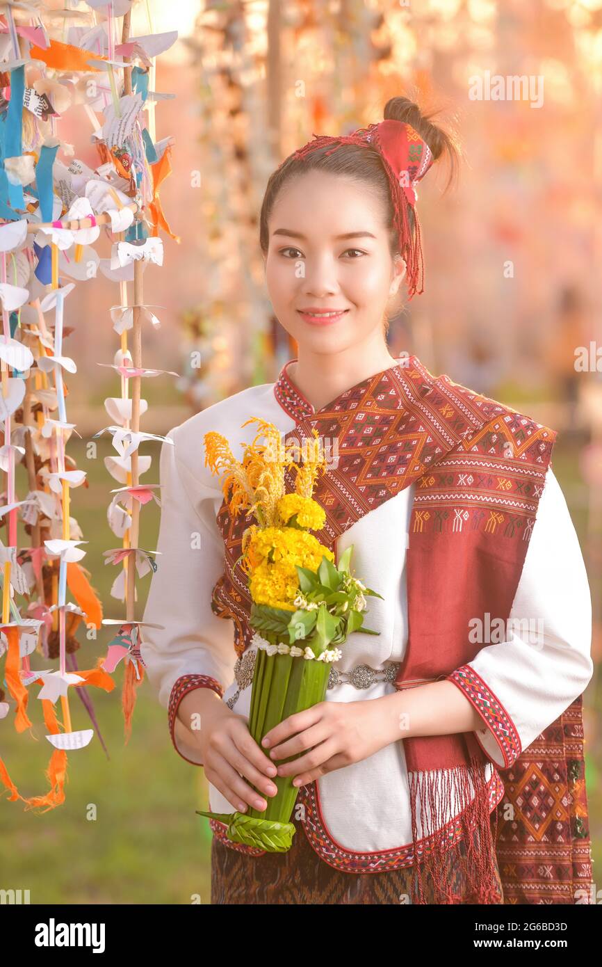 Retrato de una mujer sonriente con ropa tradicional tailandesa sosteniendo flores, Tailandia Foto de stock