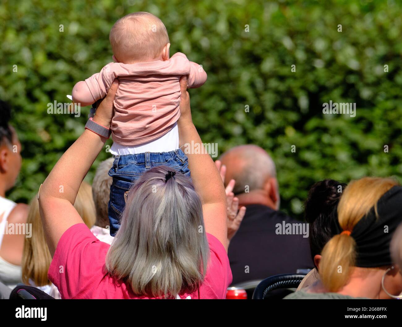 Mujer sosteniendo al bebé para ver lo que está sucediendo. Foto de stock