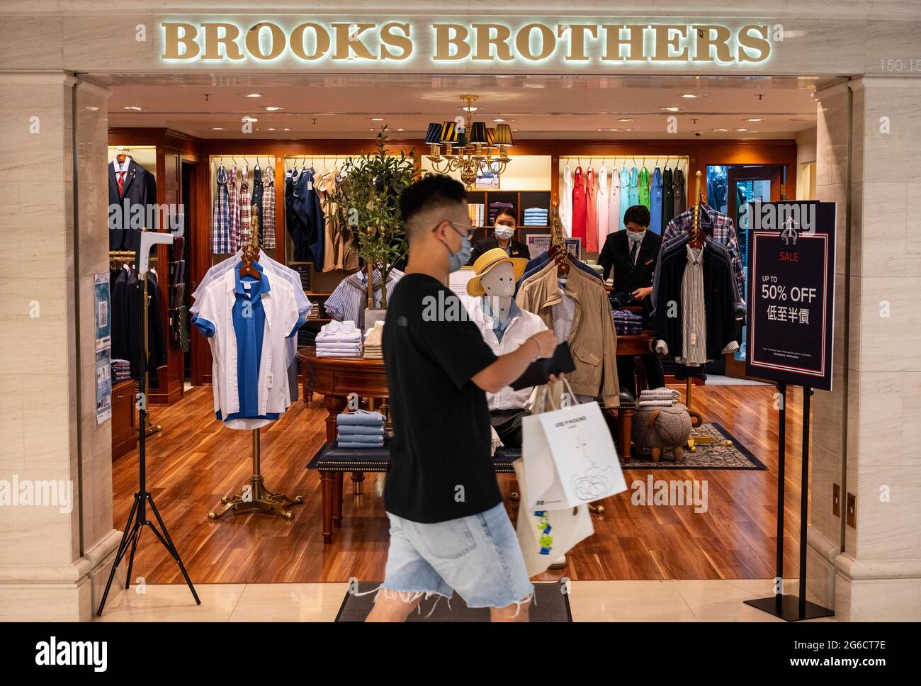 Hong Kong, 05th de julio de 2021. Un hombre que lleva bolsas de compras pasa por la marca ropa americana para hombres, Brooks Brothers, tienda vista Hong Kong. Crédito: