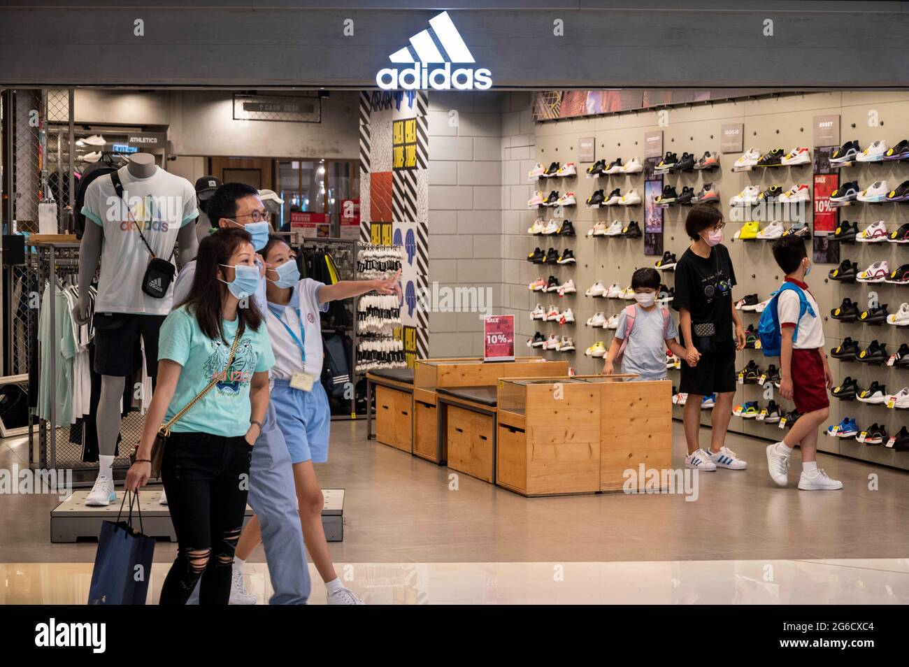 Hong Kong, China. 25th de junio de 2021. Una familia pasa por delante de la multinacional alemana de ropa deportiva tienda Adidas y logotipo en Hong Kong. Crédito: Miguel Candela/SOPA Images/ZUMA