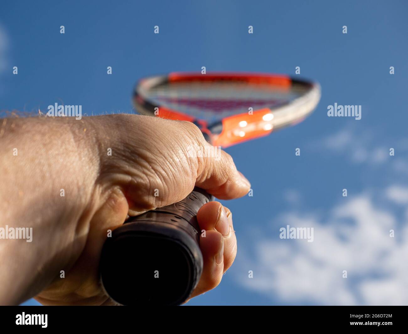 Hombre sosteniendo una raqueta de tenis mirando hacia arriba hacia un cielo  azul de verano Fotografía de stock - Alamy