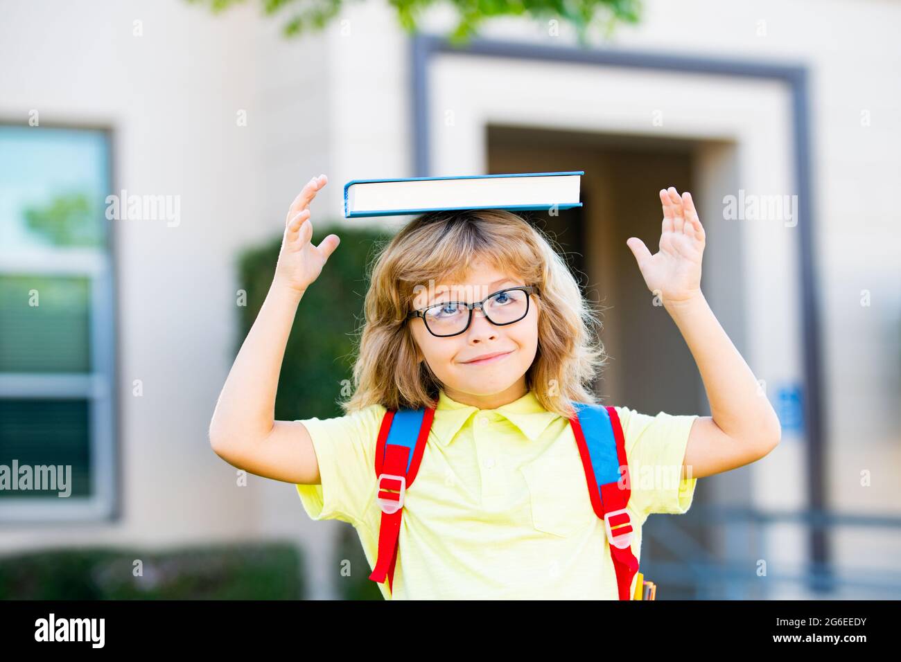Niño estudiante sonriente usando la mochila de la escuela y sosteniendo un libro de ejercicios. Retrato de alumno feliz fuera de la escuela primaria. Primer plano de Foto de stock