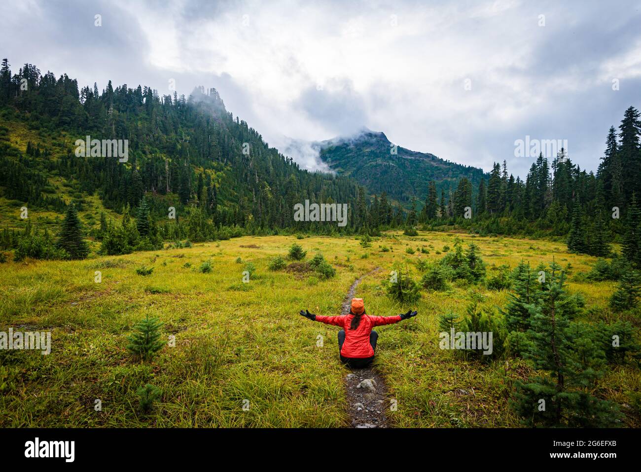 Excursionista en el Parque Nacional Olímpico sentado en el sendero que abarca las montañas Foto de stock