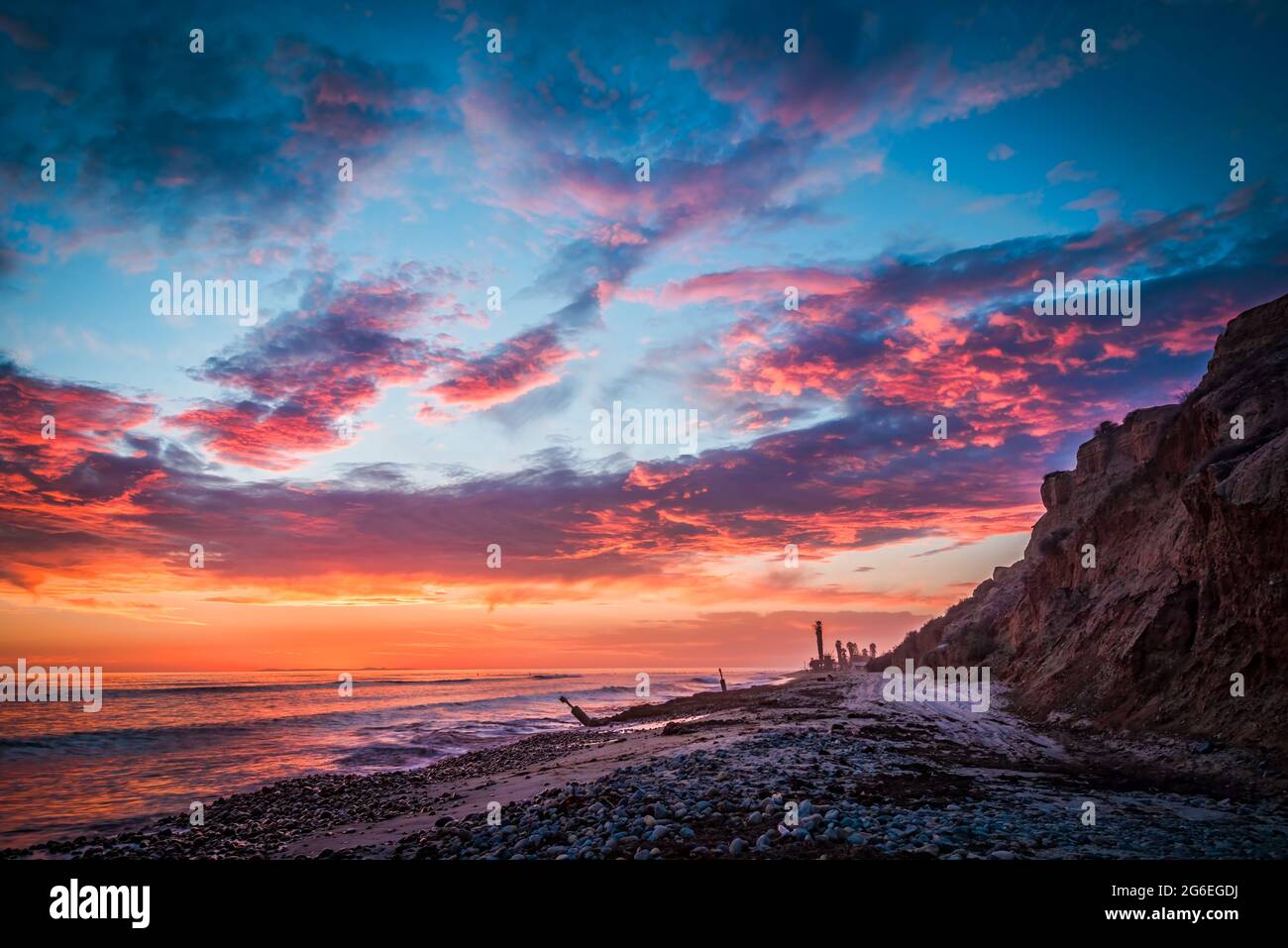 Hermosa puesta de sol en la playa con una costa rocosa Foto de stock