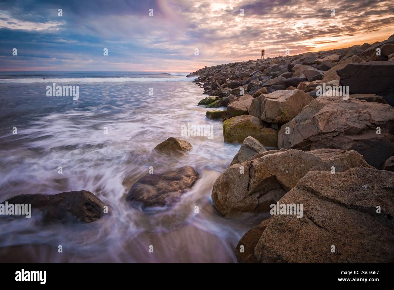 Larga exposición surf a lo largo de un muelle de playa al atardecer Foto de stock