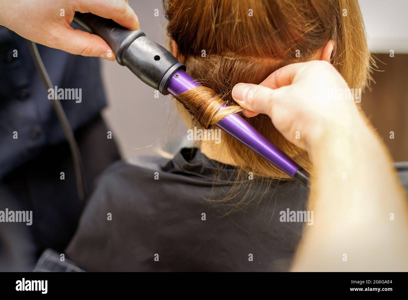 Primer plano de las manos del estilista con una plancha para rizos de pelo  en un salón de belleza Fotografía de stock - Alamy