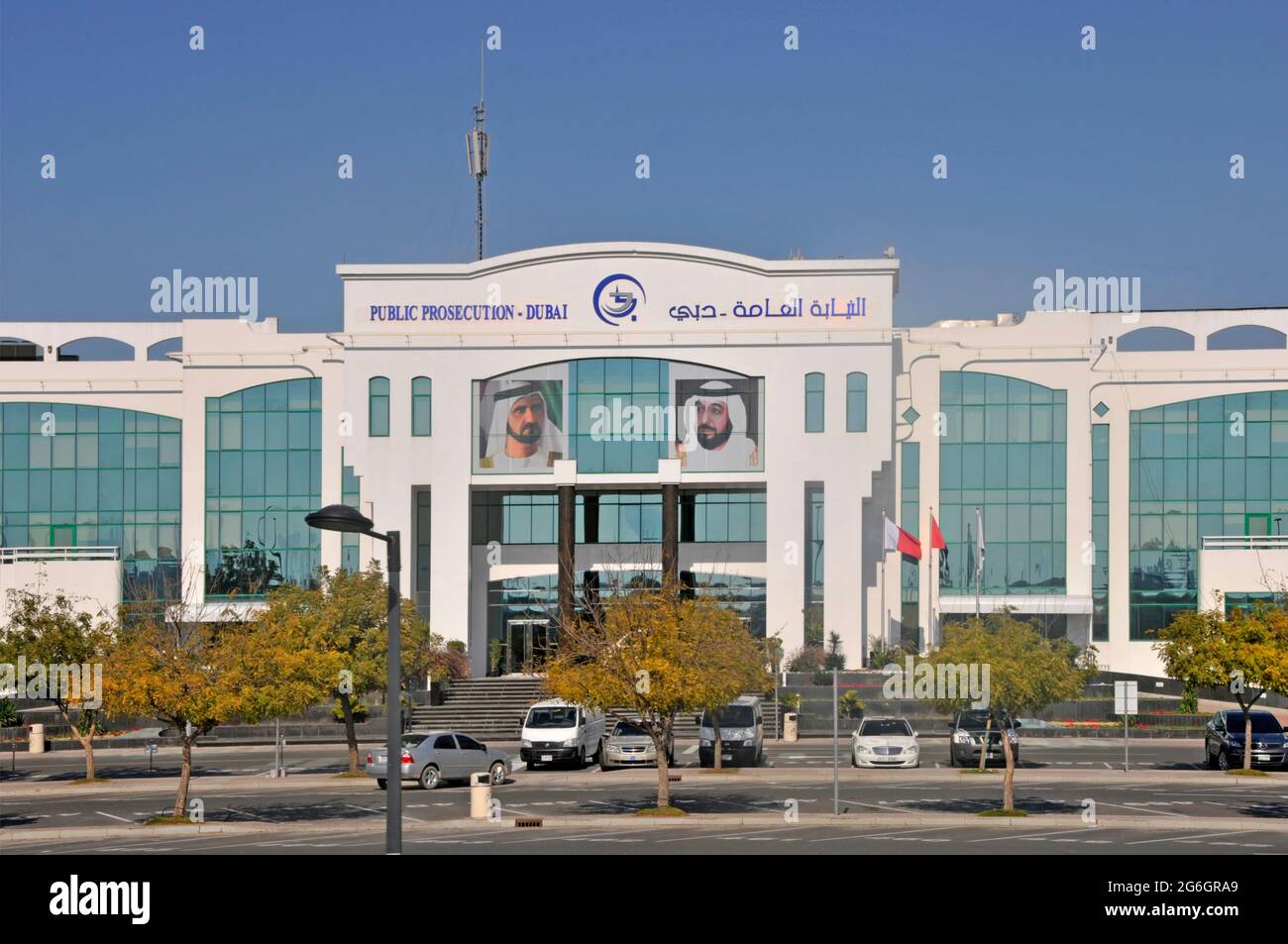 Letreros bilingües sobre la fachada frontal y la entrada del Ministerio Público de Dubai Edificio de la fiscalía masculina retratos y cielo azul Emiratos Árabes Unidos Emiratos Árabes Unidos Foto de stock