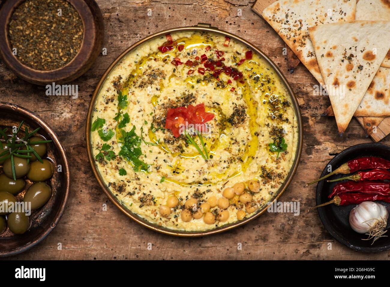 Salsa hummus sumergiera hecha de garbanzos, sésamo y otros ingredientes, utilizada tradicionalmente en la cocina mediterránea y de Pascua media, servida en un tazón Foto de stock