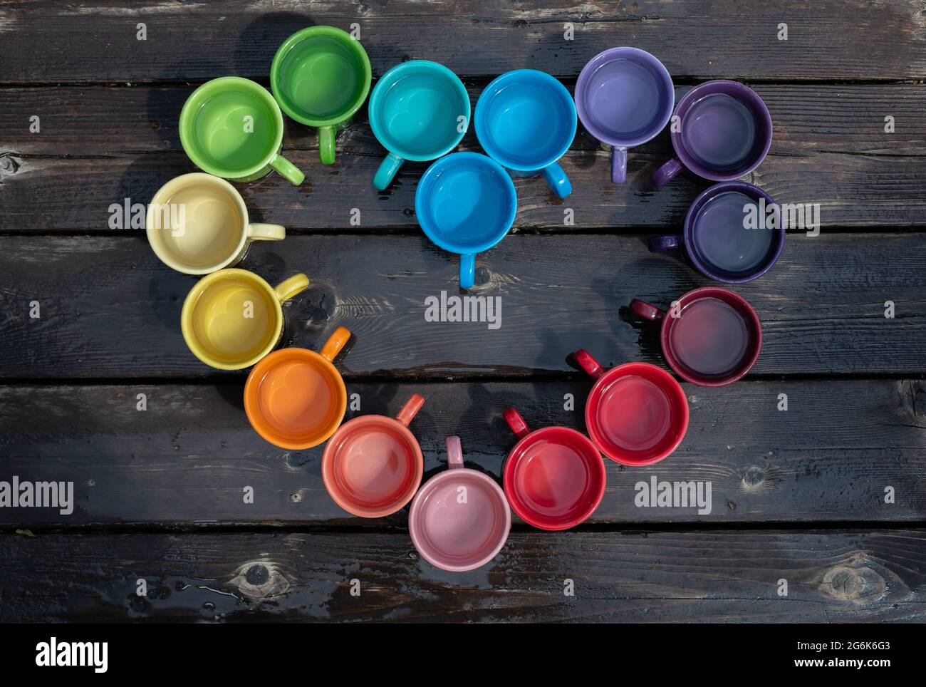 Coloridas tazas de café organizadas en forma de corazón para celebrar el mes del Orgullo Foto de stock