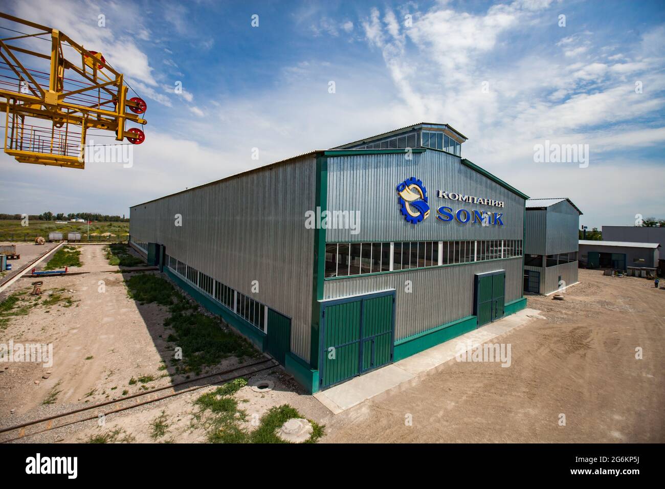 Región de Almaty, Kazajstán-junio de 06,2012: Zona industrial DE DAMU. Vista aérea del nuevo edificio de la fábrica Sonik. Puertas verdes, ferrocarril, grúa amarilla gantry lef Foto de stock