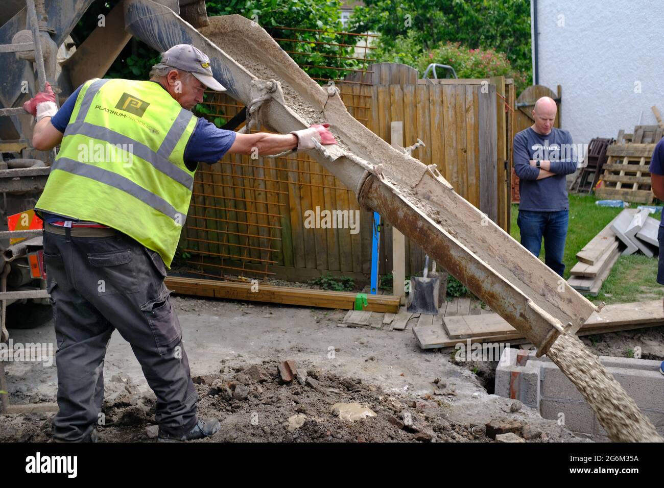 Verter cemento para una extensión de construcción en Bristol, Reino Unido con el dueño de la casa mirando. Foto de stock