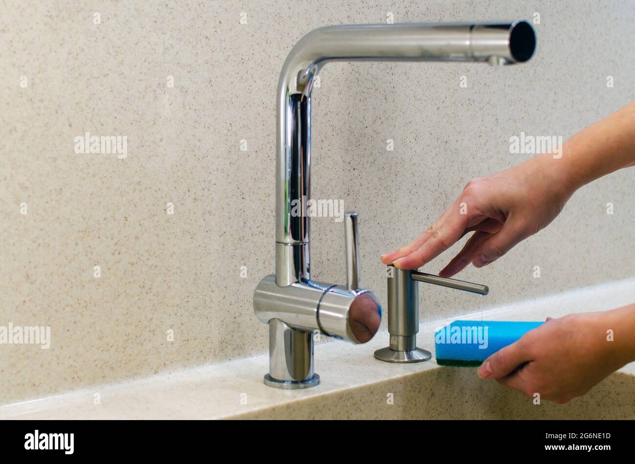 Una mujer usa un dispensador de jabón líquido en la cocina, una esponja  para lavar los platos. Mezclador de agua cromado brillante. Encimera de  mármol y fregadero Fotografía de stock - Alamy