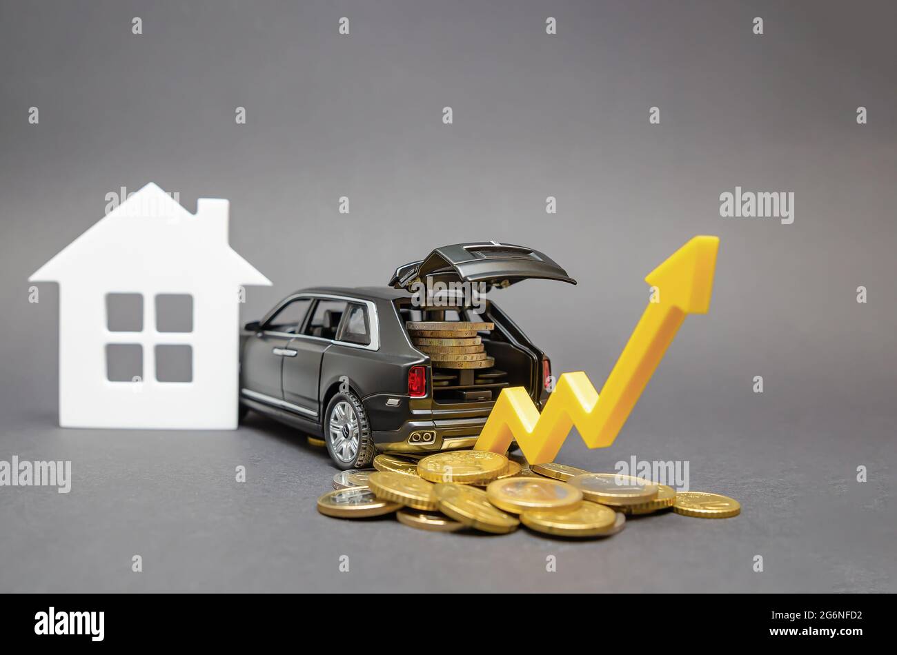 Crecimiento de los ingresos de la población. Coche con monedas en el tronco sobre fondo negro. Flecha apuntando hacia arriba como un concepto para mejorar el nivel de vida. Foto de stock