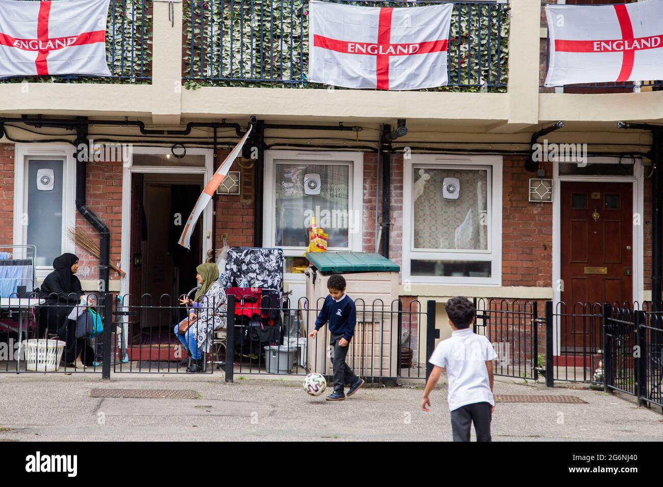 Londres, Reino Unido. 7th de julio de 2021. Los niños juegan en la finca Kirby en Bermondsey, al sudeste de Londres. Una vivienda se ha cubierto con banderas de Inglaterra por delante del partido semifinal contra Dinamarca. Crédito: Thabo Jaiyesimi/SOPA Images/ZUMA Wire/Alamy Live News Foto de stock