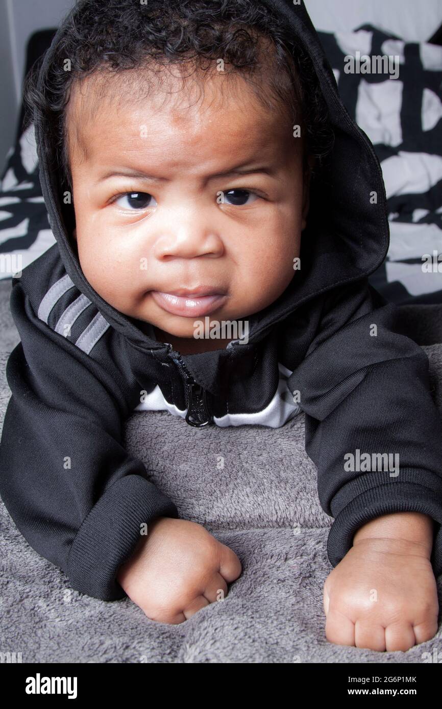 Carismático bebé de 4 meses. Un niño Hip hop niño. Retrato de un lindo bebé urbano, con un traje de adidas gris de stock -