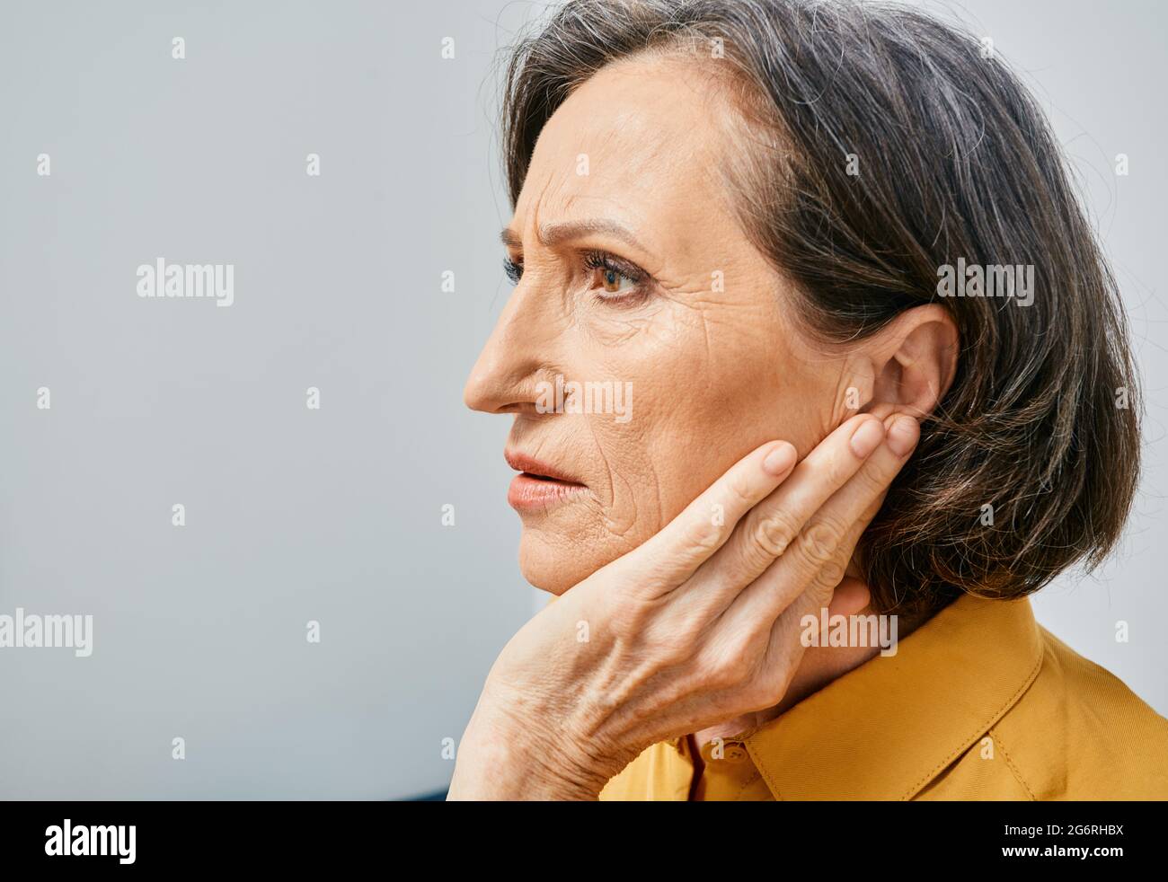 Pérdida auditiva. Mujer madura con problemas de audición al tocar el oído con la mano. Vista lateral, dolor de oídos Foto de stock