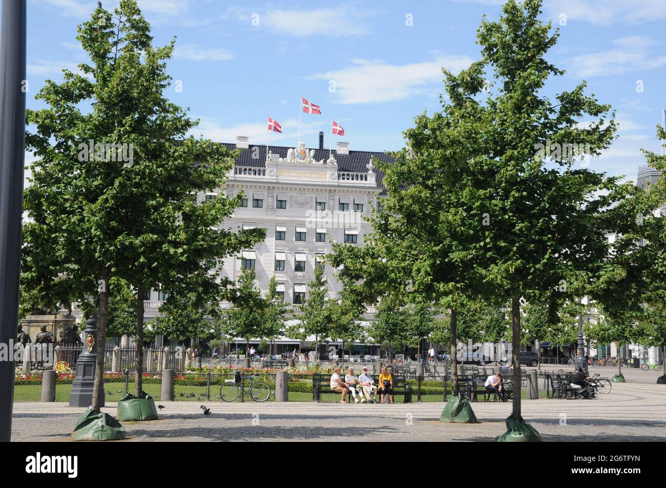 Copenhague, Dinamarca. 08 2021, la gente disfruta de los veranos calurosos del sol en el Kongen nytorv con flores y plantas y el edificio blanco es grande llamado Hotelo Foto de stock