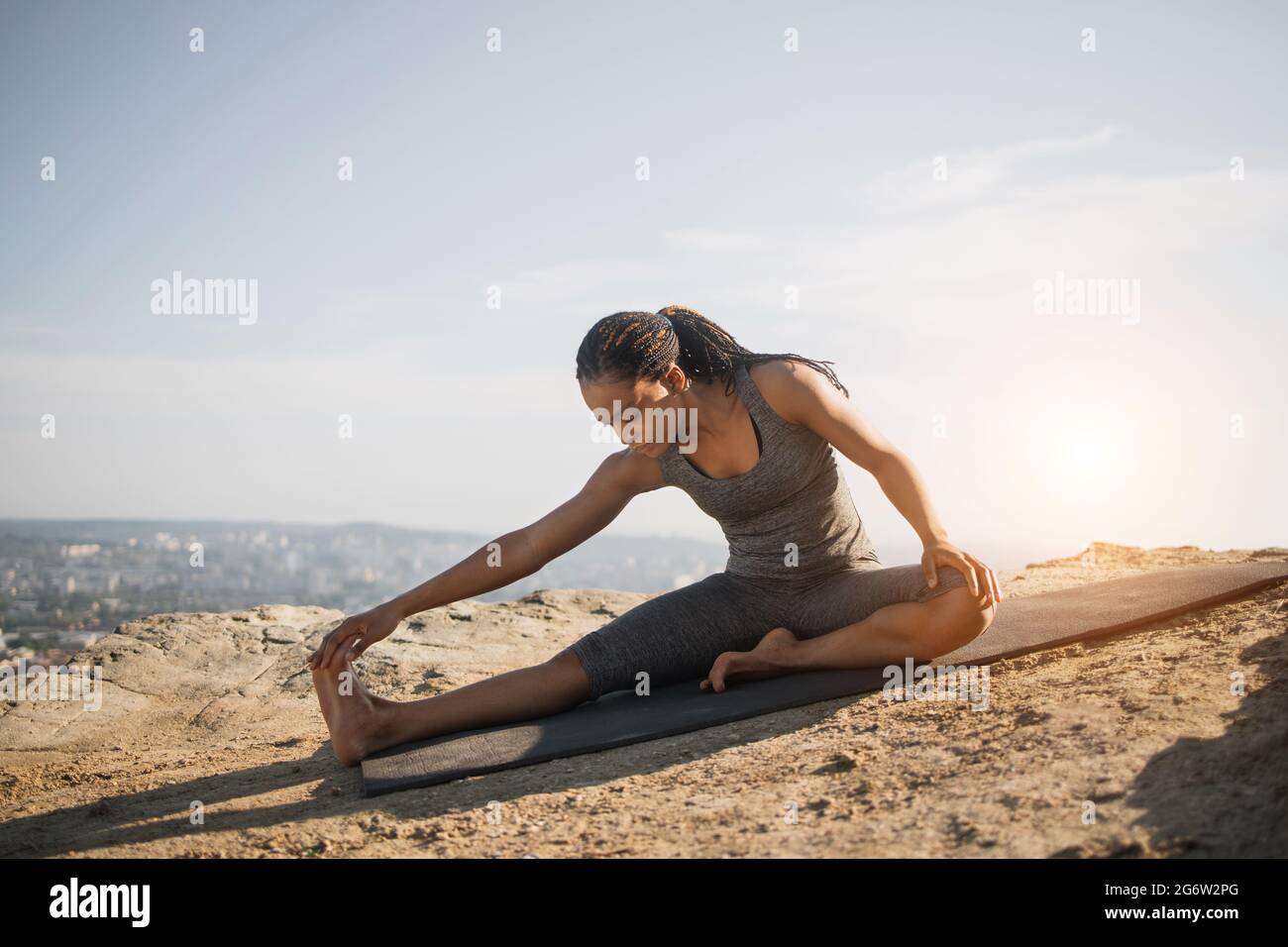 Fitness mujer negra con ropa deportiva estirando cuerpo en colchoneta de  yoga al aire libre. Mujer esbelta haciendo ejercicio por la mañana al aire  libre. Estilos de vida activos y saludables Fotografía