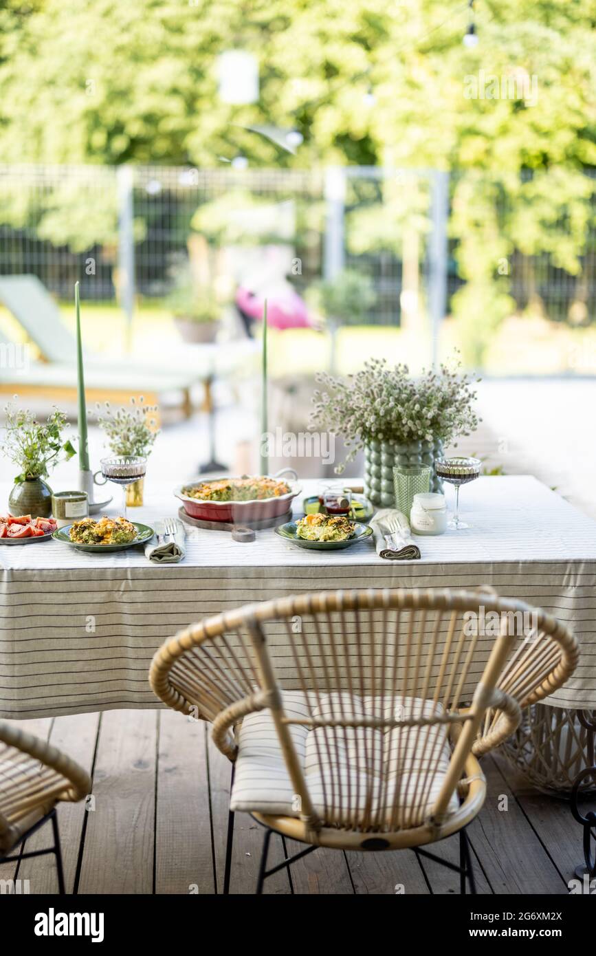 Mesa en el jardín está cubierta con una mantel y decorada con flores y  velas con comida para dos personas. Cena de verano al aire libre Fotografía  de stock - Alamy
