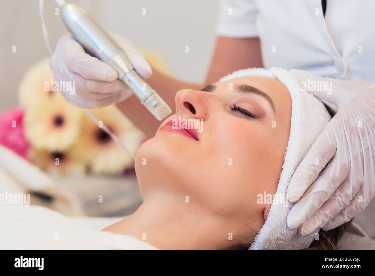 Primer plano de la cara de una mujer que se relaja en un moderno centro de belleza durante el tratamiento facial con tecnología innovadora para suavizar arrugas y rejuv Foto de stock