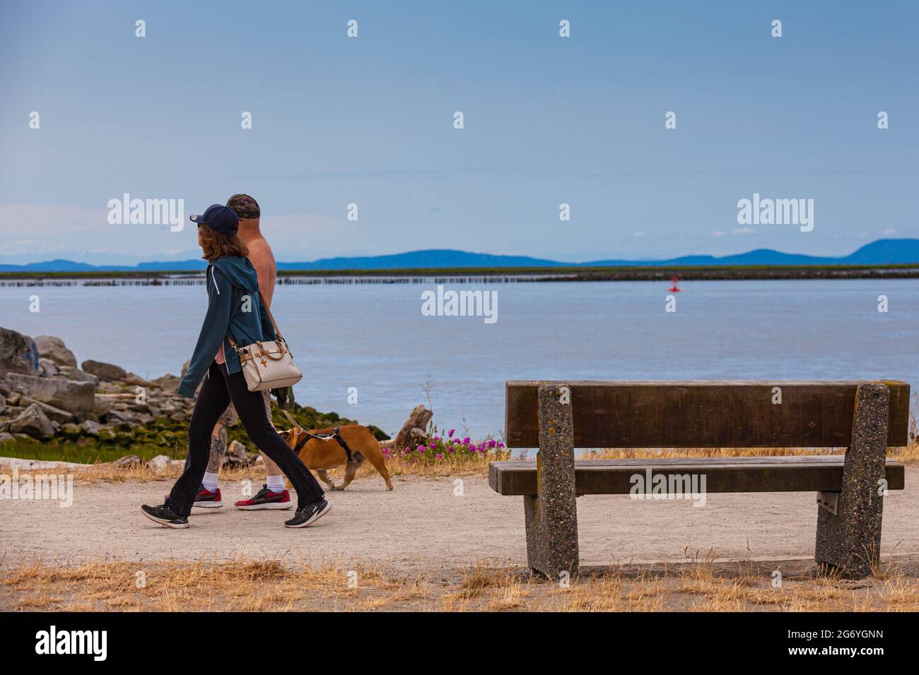 Una pareja caminando a su perro a lo largo de la orilla del río Garry Park en Steveston British Columbia Canadá Foto de stock