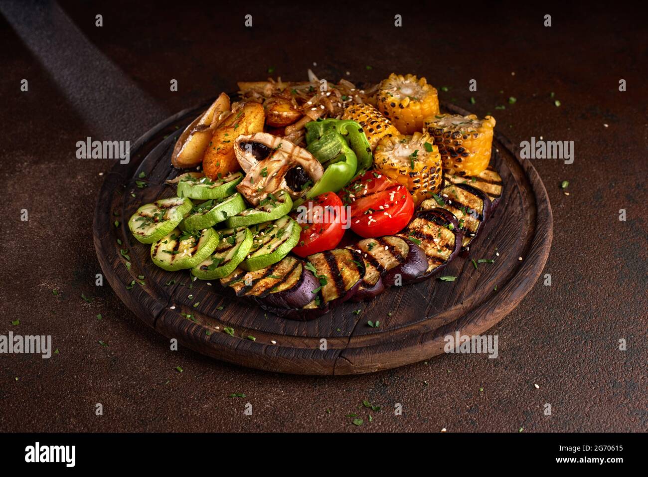 pancarta. una gran porción de verduras fritas de colores y setas en una bandeja de madera sobre un fondo oscuro. Foto de stock