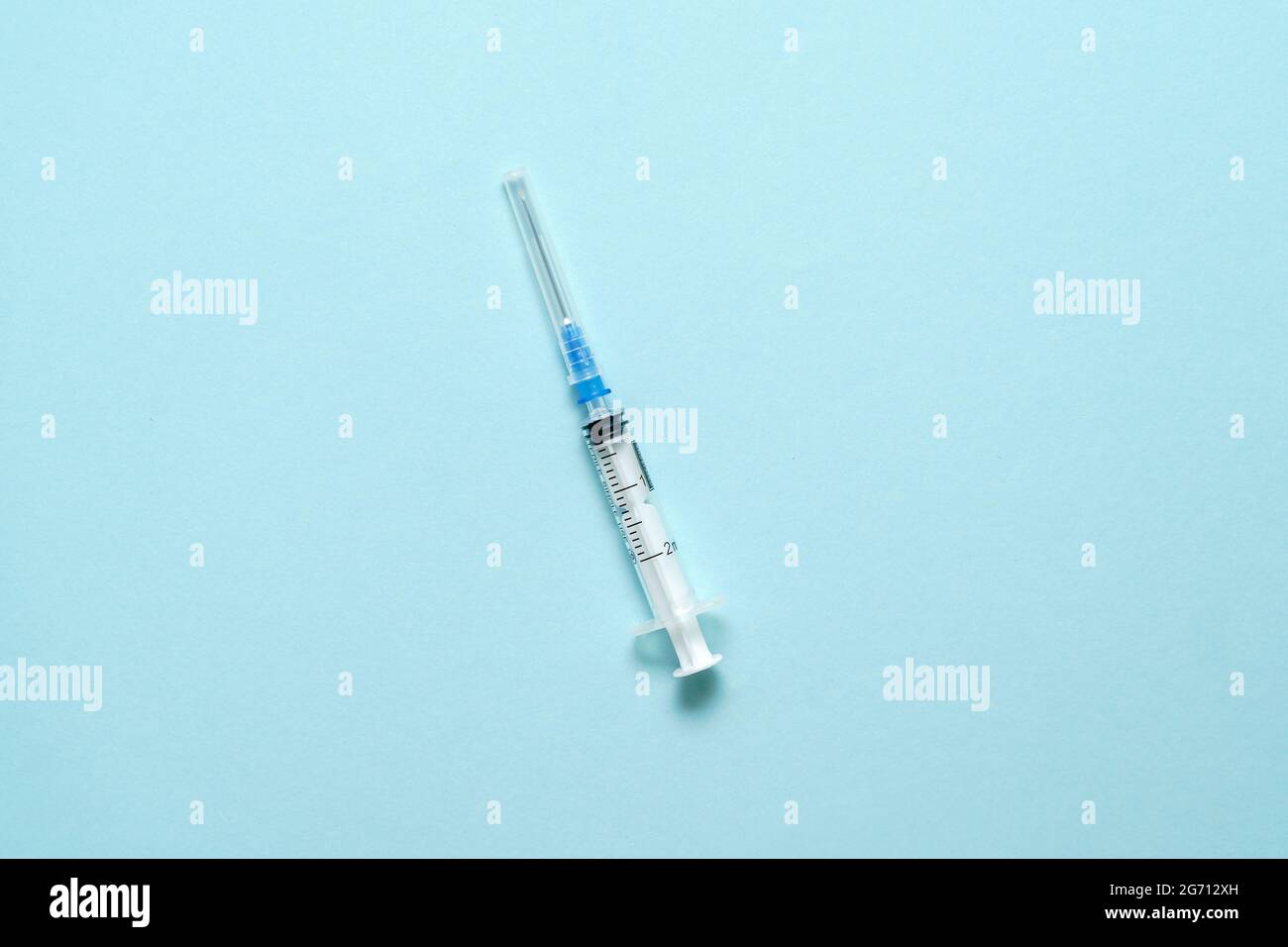 Vista superior de la jeringa de inyección sobre fondo azul. Concepto mínimo de vacuna. Tratamiento médico de la diabetes con insulina. Vacuna Covid-19. Antivax Foto de stock