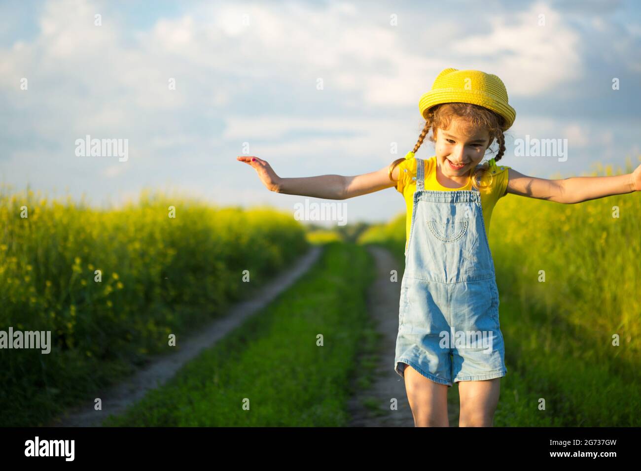 Chica alegre en un sombrero amarillo en un campo de verano ríe y sonríe. Alegría, tiempo soleado, holidays.repelente para mosquitos e insectos. Estilo de vida, amable Foto de stock