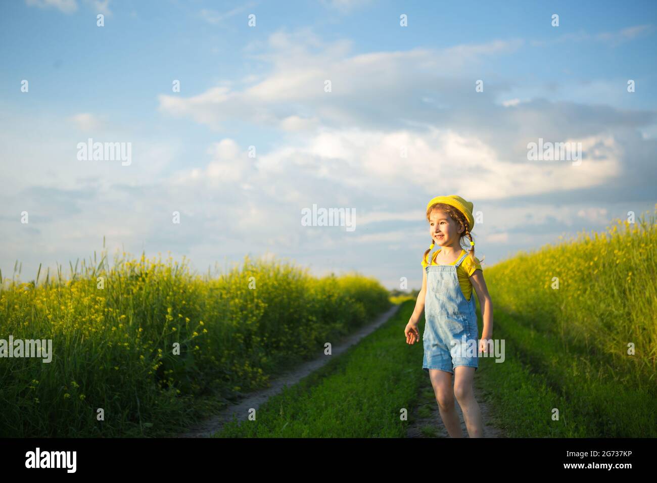 Chica alegre en un sombrero amarillo en un campo de verano ríe y sonríe. Alegría, tiempo soleado, vacaciones. Un remedio para mosquitos e insectos. Estilo de vida, amable Foto de stock