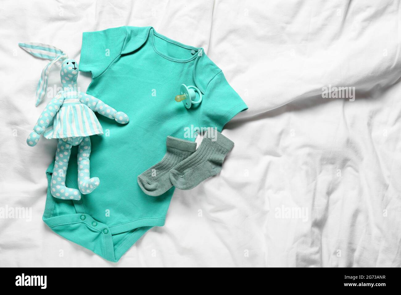 Ropa de bebé, juguete y chupete en la cama Fotografía de stock - Alamy