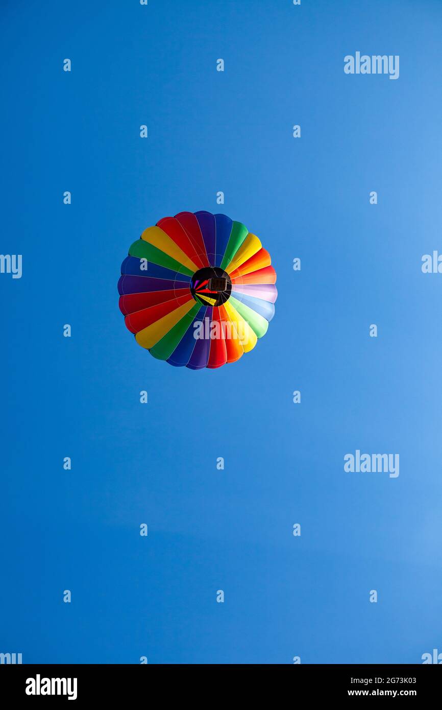 Globo de aire caliente de colores flotando sobre un cielo azul claro con espacio de copia, vertical Foto de stock