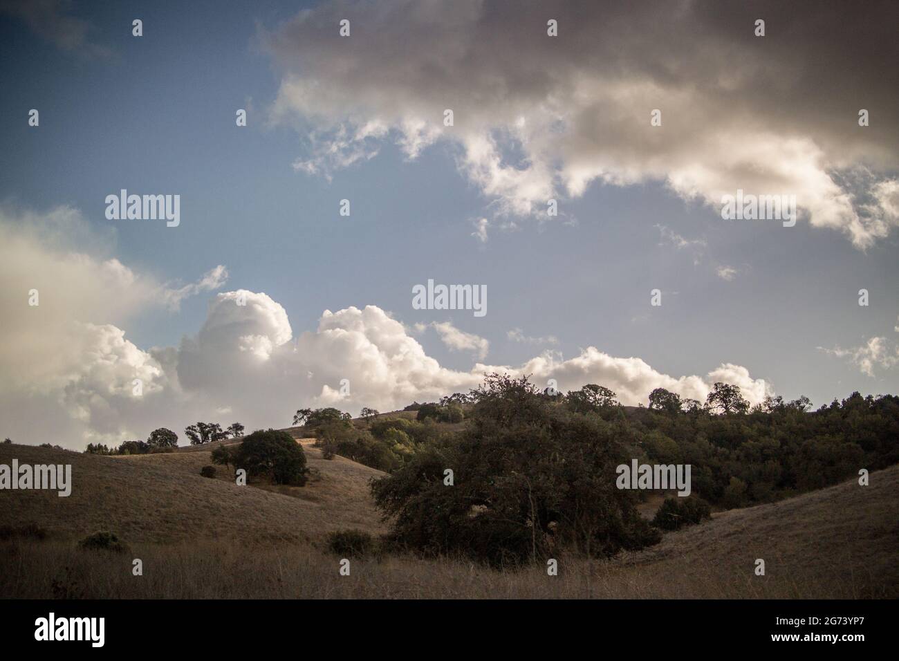 Cielos azules brillantes con nubes de lluvia gris que proyectan sombras sobre el paisaje montañoso de Santa Cruz. Foto de stock