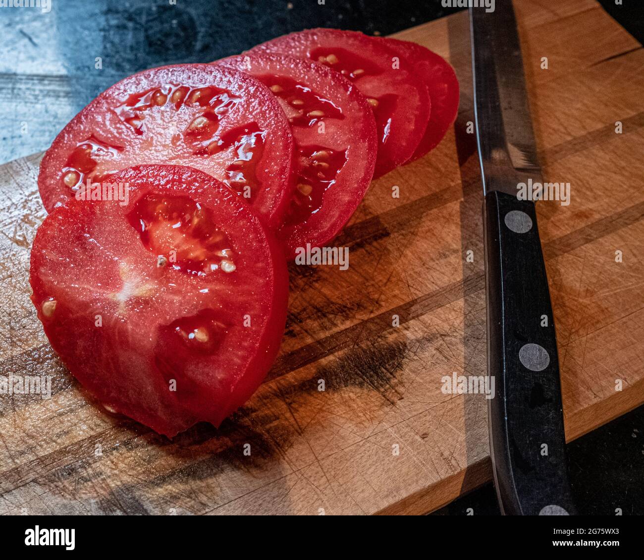 Tomates recién cortados en la tabla de cortar Foto de stock