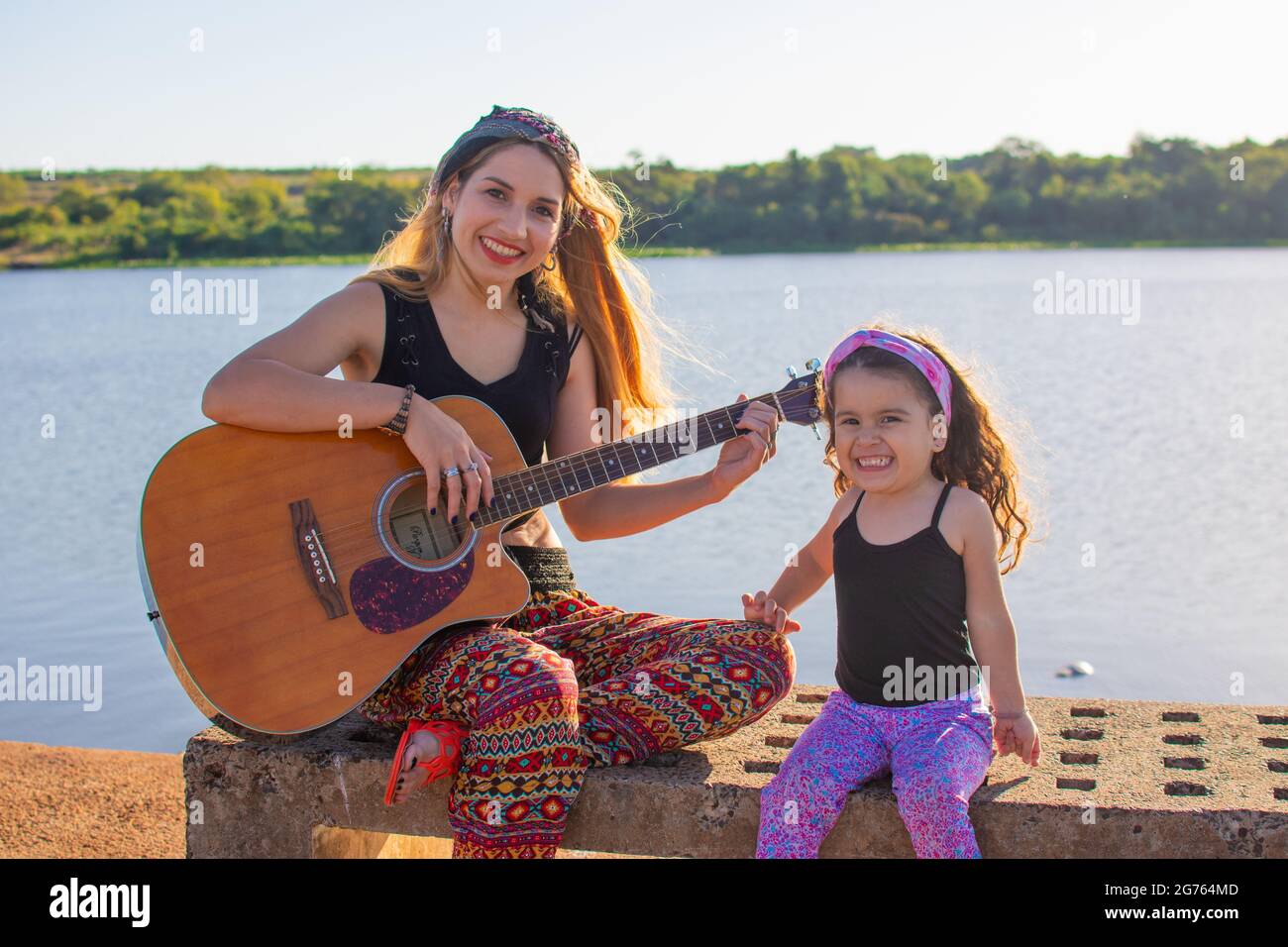 Una mujer argentina sentada en un banco con su niño tocando la guitarra y  cantando en la orilla del río Fotografía de stock - Alamy