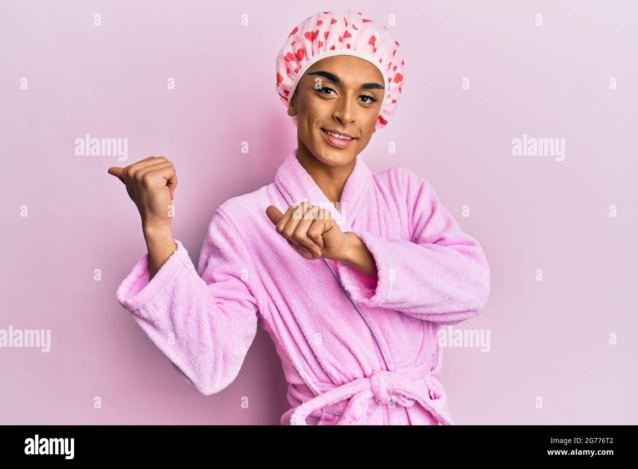 Hombre hispano con gorro de ducha y albornoz apuntando a la espalda con la  mano y los pulgares hacia arriba, sonriendo con confianza Fotografía de  stock - Alamy