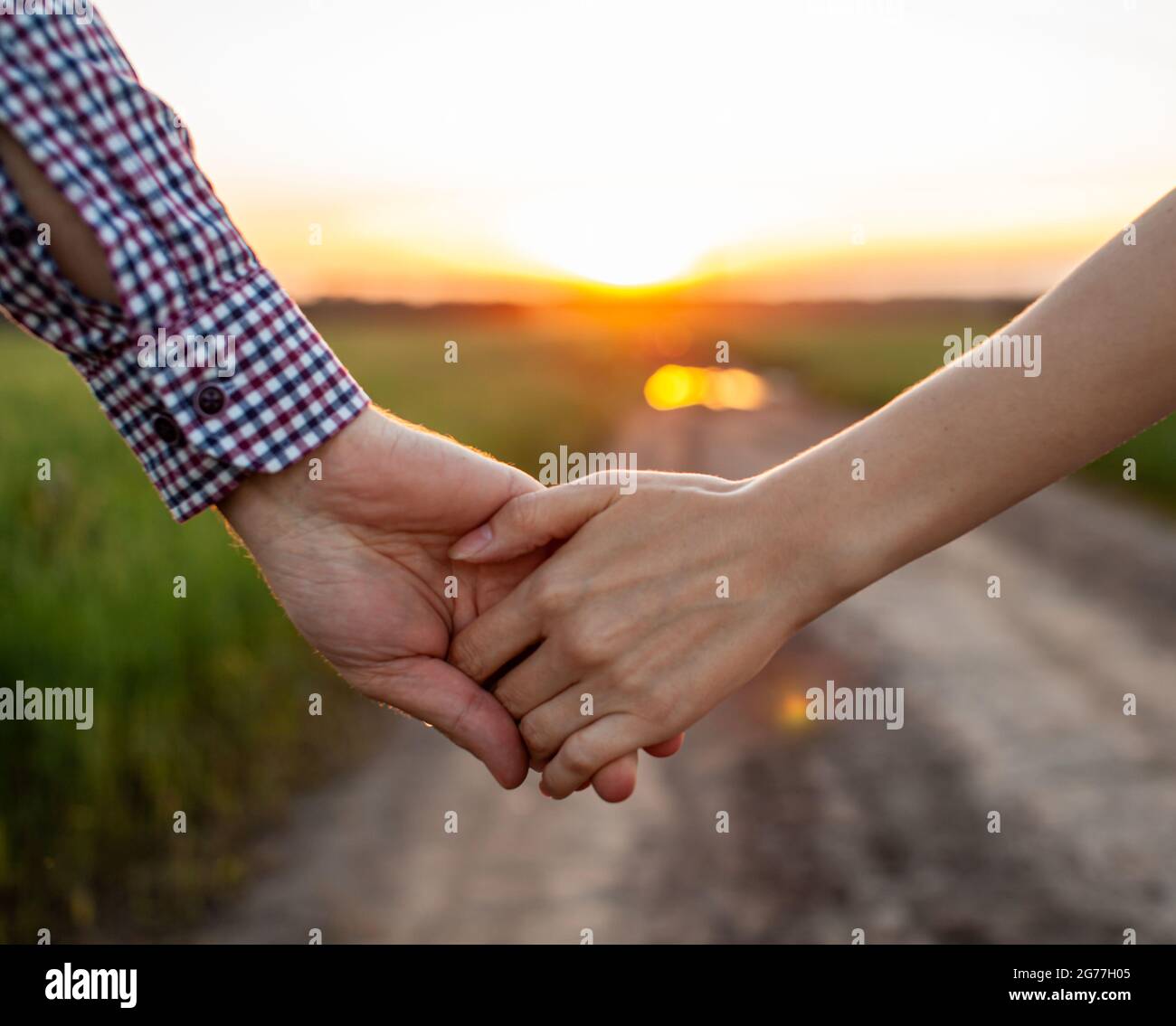 Concepto de amor. Una pareja sosteniendo la mano durante la puesta de sol, un símbolo de amor y relación feliz. Una joven pareja enamorada camina a través de un campo al atardecer, Concepto de amor. Una pareja sosteniendo la mano durante la puesta de sol, un símbolo de amor y relación feliz. Una joven pareja enamorada camina a través de un campo al atardecer,
