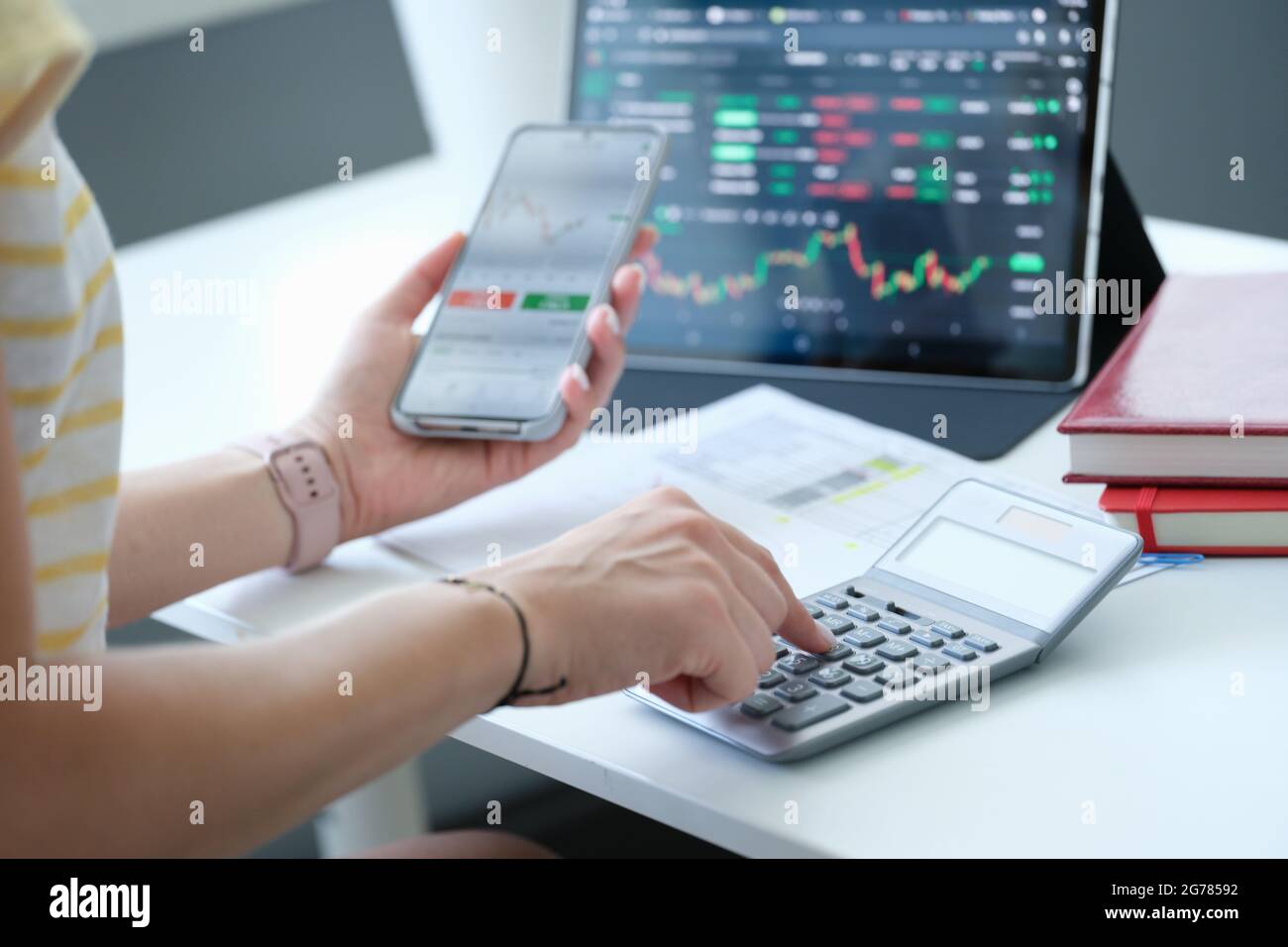 Businesswoman con calculadora de smartphone y portátil calcula los cambios de cambio de la bolsa de valores Foto de stock