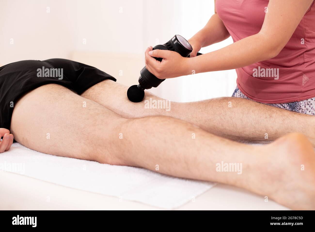 https://c8.alamy.com/compes/2g78c5d/pistola-de-masaje-fisioterapeuta-femenina-joven-que-utiliza-una-pistola-de-masaje-manual-para-aliviar-el-dolor-muscular-de-las-piernas-durante-la-sesion-de-fisioterapia-2g78c5d.jpg