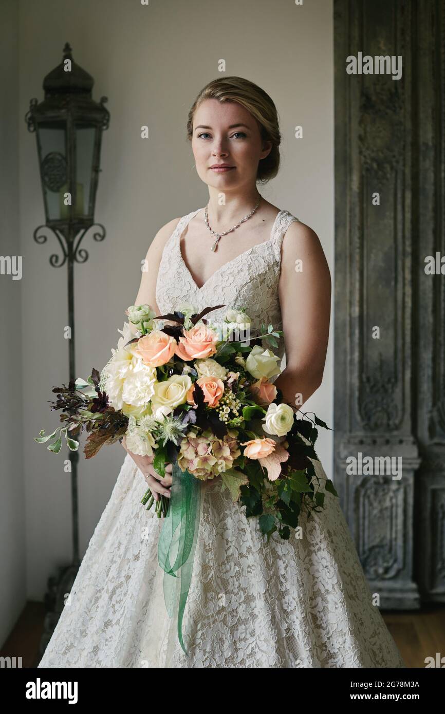 Novia en vestido de boda de marfil con un de encaje y un gran ramo floral pastel Fotografía de stock -