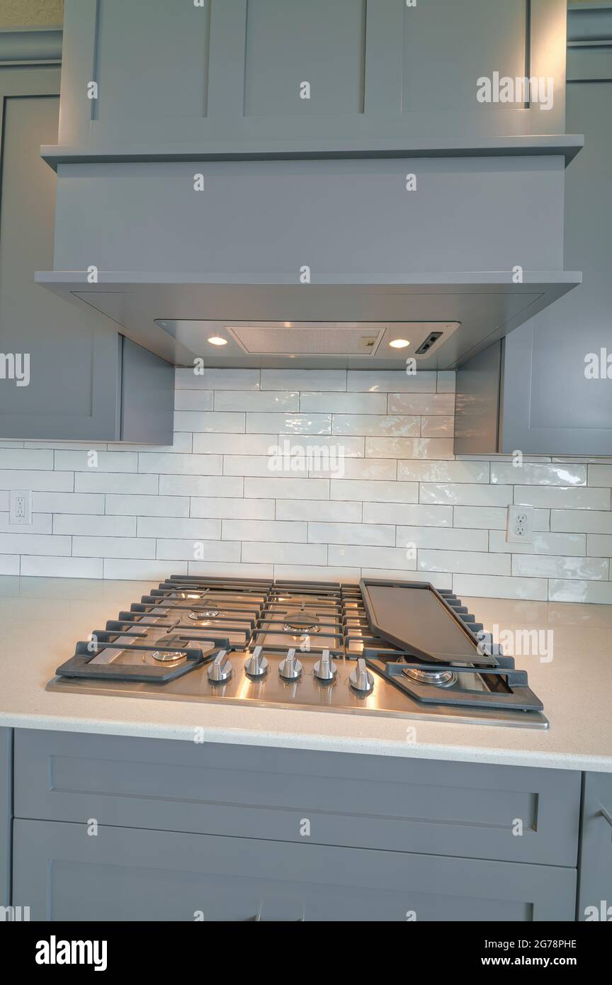 Parrilla y campana de escape contra armarios grises y salpicadero blanco de  la cocina Fotografía de stock - Alamy