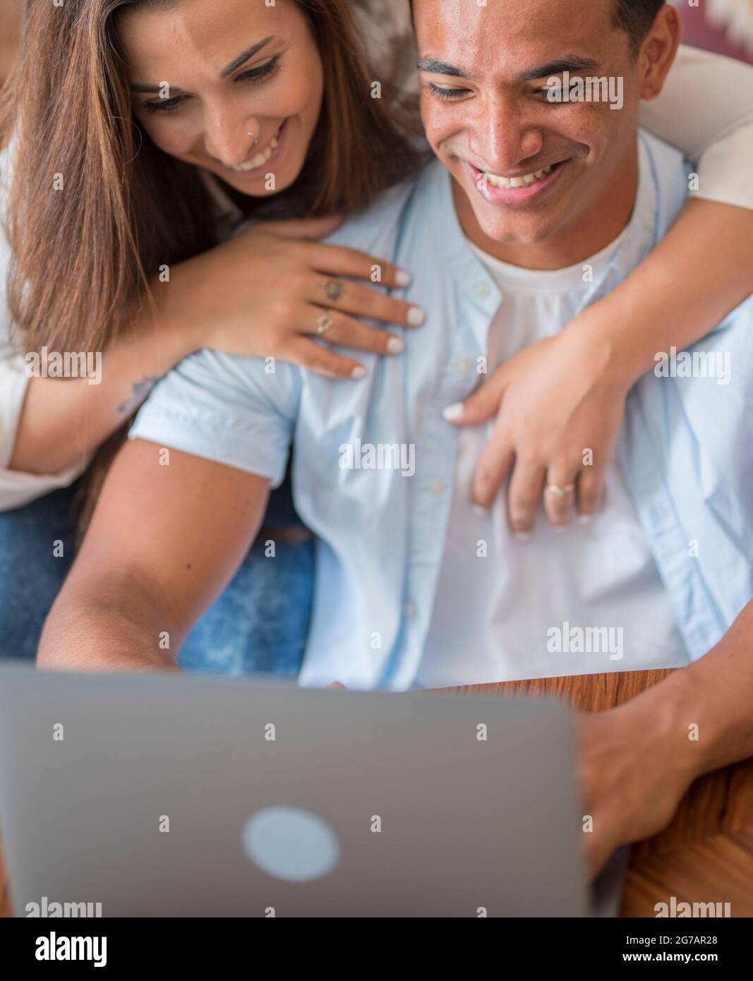 Primer plano de la pareja joven que trabaja en el portátil en casa - la gente feliz disfrutar de la computadora en línea y la conexión junto con la diversión y la felicidad - el amor y la vida - interracial relación hombre y mujer Foto de stock