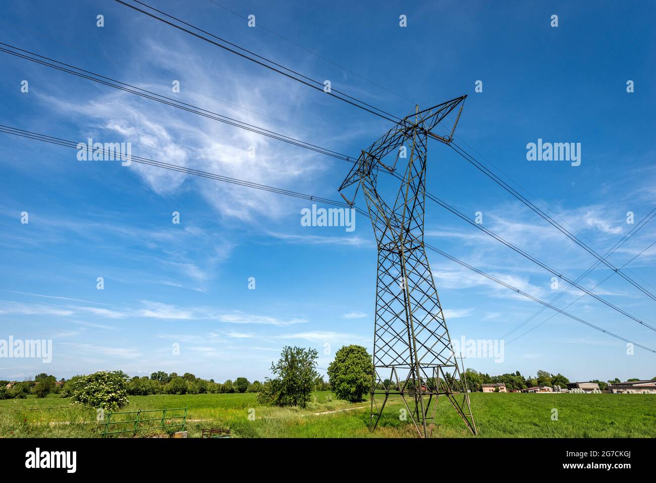 Torre de alta tensión, línea eléctrica con cables eléctricos y aislantes en  el campo contra un cielo azul con nubes. Padan Plain o valle del Po, Italia  Fotografía de stock - Alamy