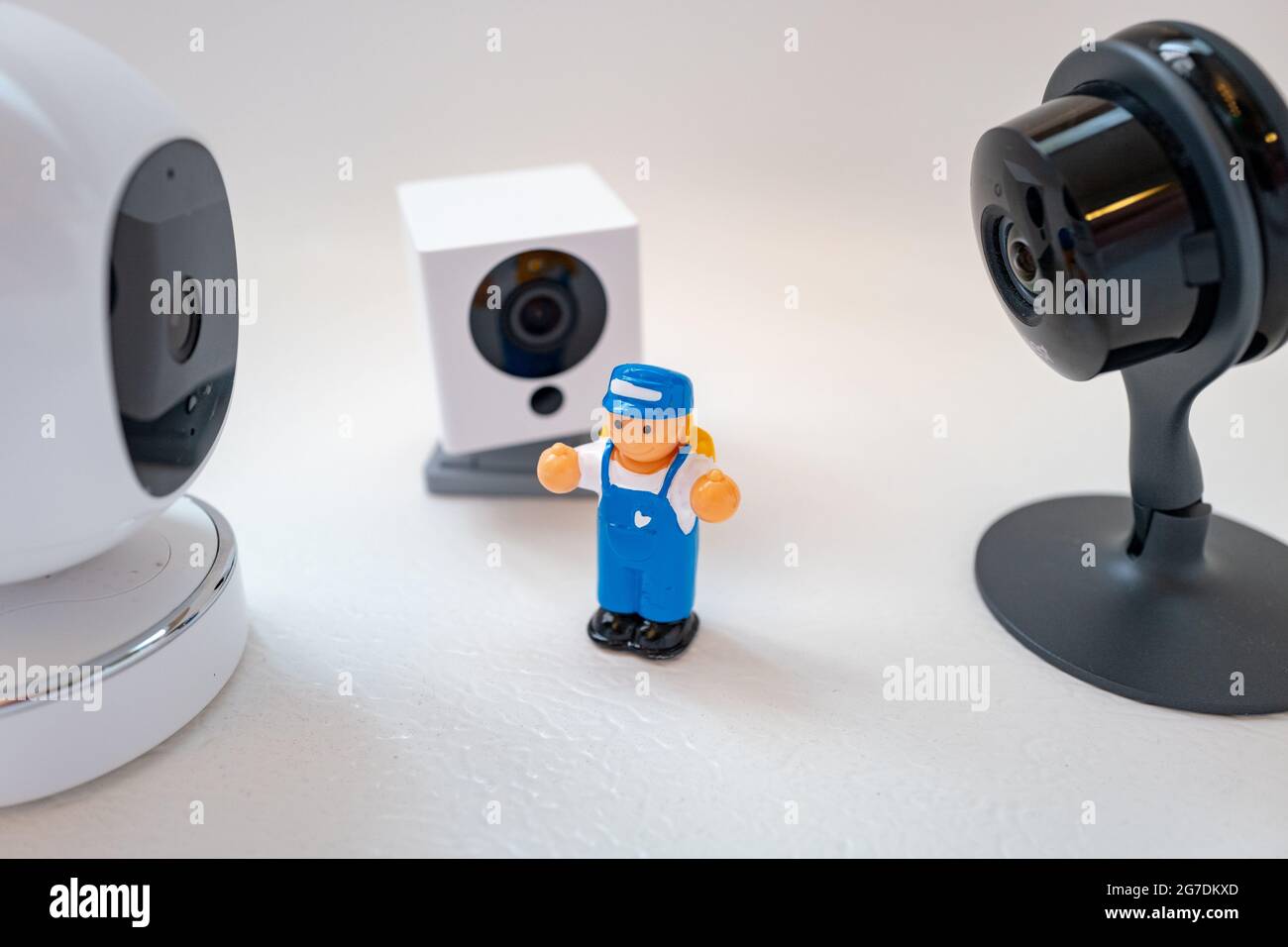 Imagen ilustrativa de un juguete plástico de un niño rodeado de cámaras de seguridad de Google Nest, Simcam y Wyze sobre un fondo blanco, sugiriendo vigilancia masiva, en San Ramon, California, noviembre de 20, 2020. () Foto de stock