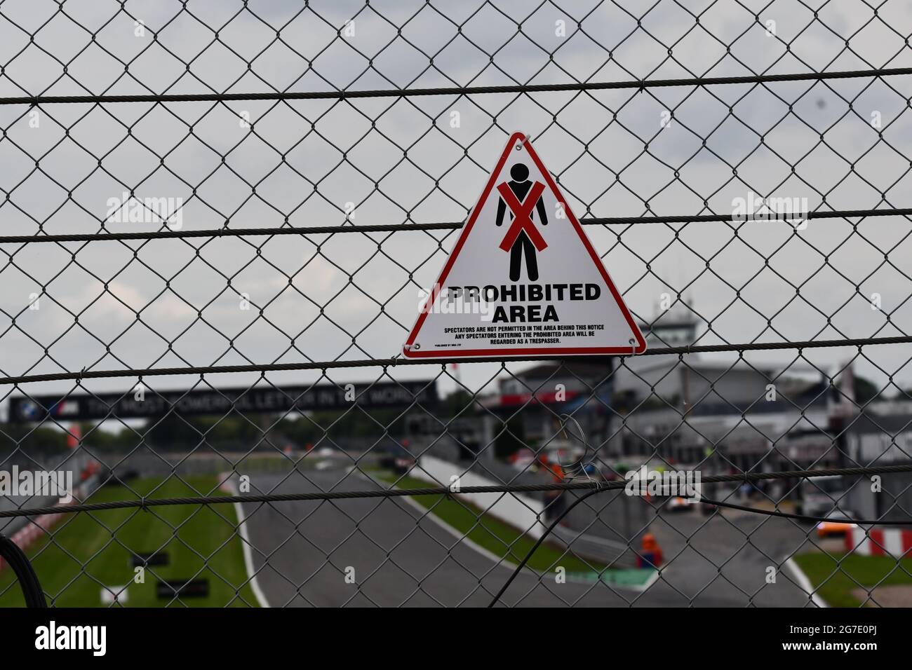 Señal de advertencia de área prohibida en una valla de seguridad sobre un circuito de carreras Foto de stock