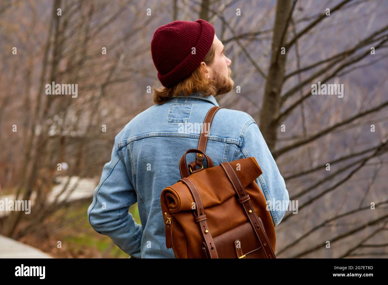 hipster viajero hombre disfrutando de un entorno natural, de pie en  contemplación. Hombre con chaqueta vaquera con mochila marrón de cuero  camina solo al aire libre Fotografía de stock - Alamy