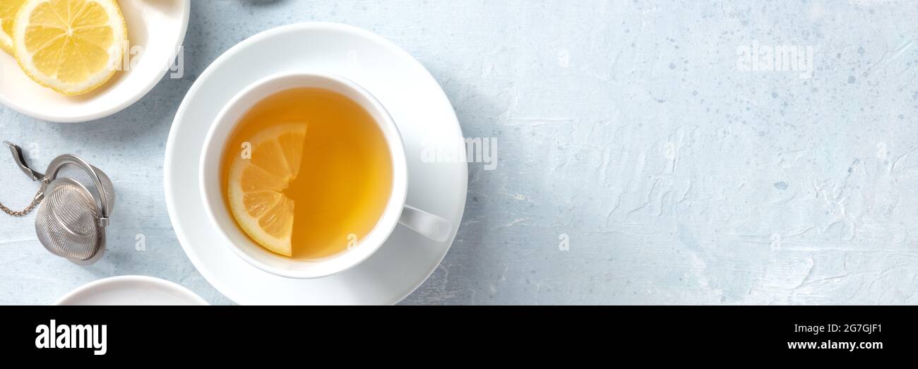 Panorama de té de limón con espacio de copia. Una taza de té con una rodaja de limón fresco, rodada desde la parte superior sobre un fondo de pizarra Foto de stock